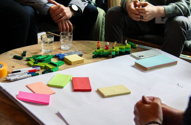 Teilnehmende beim NEGZ-Workshop 2025 arbeiten in Kleingruppen mit LEGO-Steinen, Post-its und Markern an Konzepten für Datenkultur und interaktive Dashboards