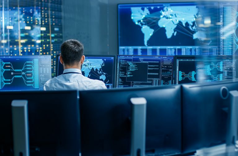 Fachkraft vor mehreren Monitoren mit Datenvisualisierungen – symbolisiert datenbasierte Steuerung und digitale Vernetzung in der öffentlichen Verwaltung